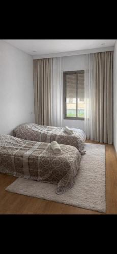 a bedroom with two beds and a window at résidence avec piscine wifi et parking gratuit in Bouskoura