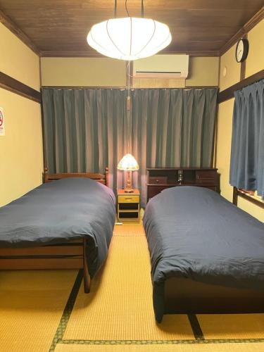 a bedroom with two beds and a chandelier at Lodging House NAO in Aomori