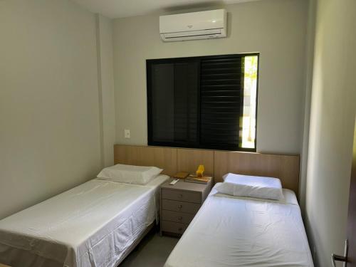 two beds in a small room with a window at Apartamento confortável, calmo e bem localizado in Lucas do Rio Verde