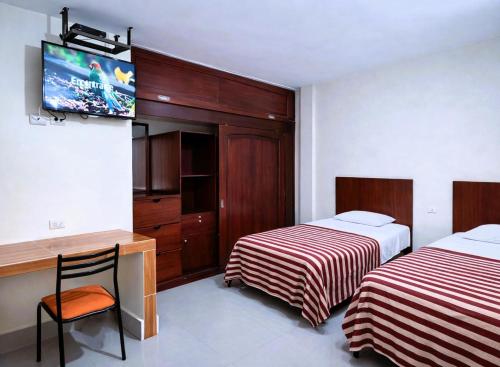 a room with two beds and a desk and a tv at Habitaciones Sky in Manta