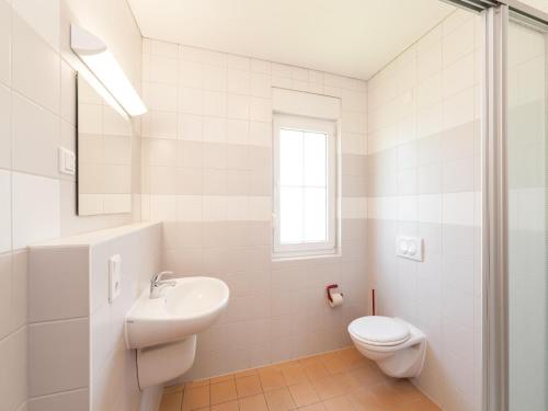 a white bathroom with a toilet and a sink at Ferienhaus im Trixi Ferienpark in Großschönau