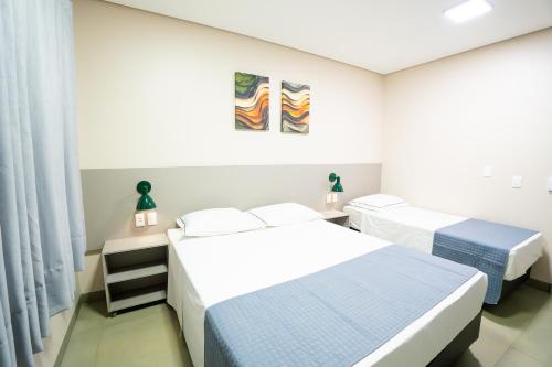 two beds in a room with white walls at Barak Hotel in Nova Mutum