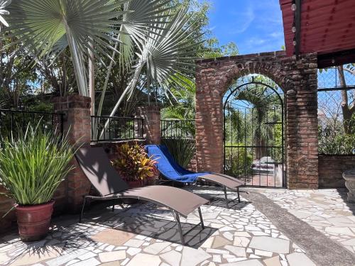 a patio with two chairs and palm trees at Villa Palmier Terrace, Garden & Serenity at PV in Puerto Vallarta