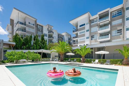 two people in inflatable tubes in a swimming pool in a apartment at Boulevard North Lakes in North Lakes