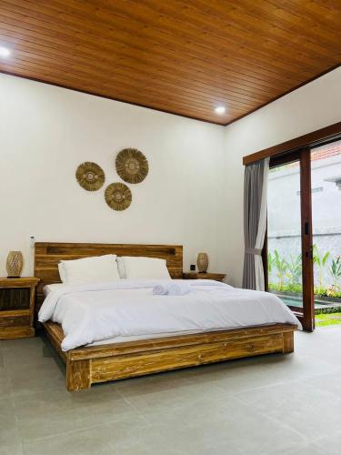 a bedroom with a large bed with a wooden headboard at Sedana Pertiwi House in Ubud