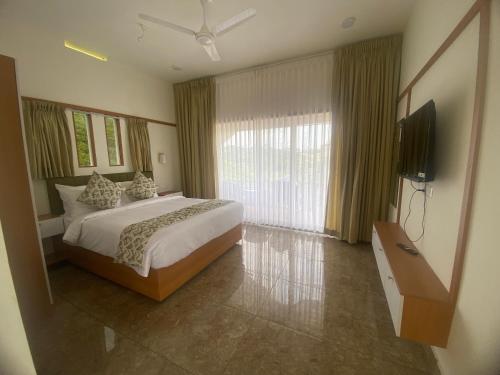 a bedroom with a bed and a flat screen tv at Misty Glen in Vagamon