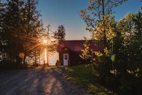 a small house with the sun shining on it at Le Huard - Lakefront & Private Dock in Sayabec