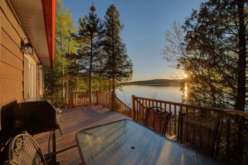 a deck with a table and chairs and a view of a lake at Le Huard - Lakefront & Private Dock in Sayabec