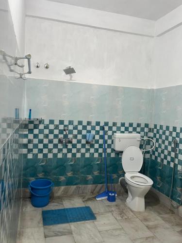 a bathroom with a toilet and a tiled wall at Aura house in Jorhat