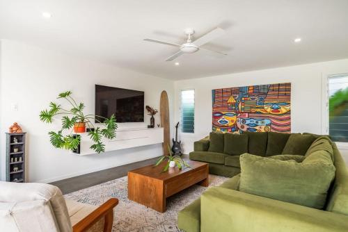 a living room with a green couch and a tv at Beachside Banksia in East Ballina
