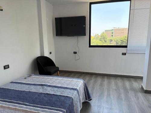 a bedroom with a bed and a tv on the wall at Estadía San Vicente in San Vicente de Cañete