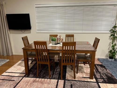 a dining room table with four chairs and a television at Rana Niwas in Rolleston