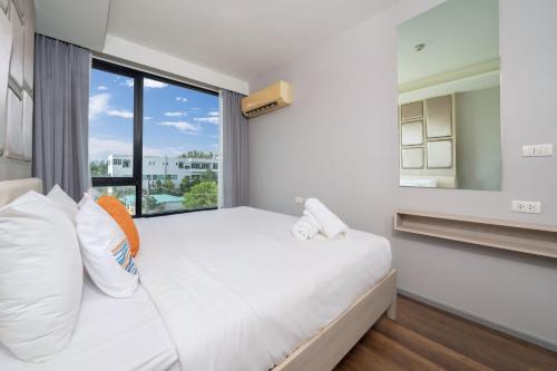 a bedroom with a bed and a large window at Surin Condo Walk to Beach with Rooftop Pool - C416 in Ban Lum Fuang
