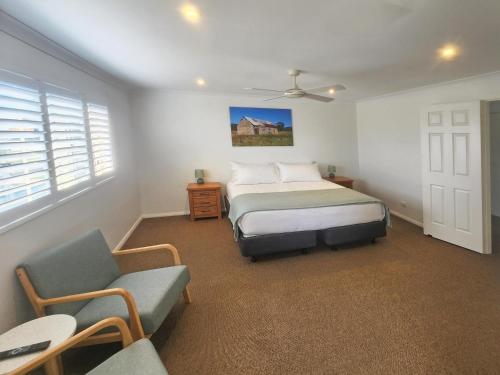a bedroom with a bed and a chair at Soldiers Motel in Mudgee