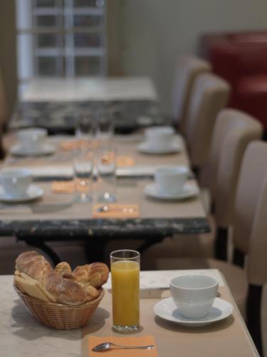 a row of tables with bread and a glass of orange juice at Hotel de La Comédie in Montpellier