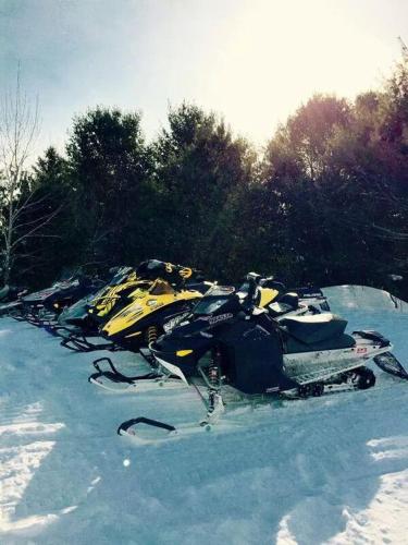 a row of snowmobiles are lined up in the snow at Little Hawk Resort & Marina in Algonquin Highlands