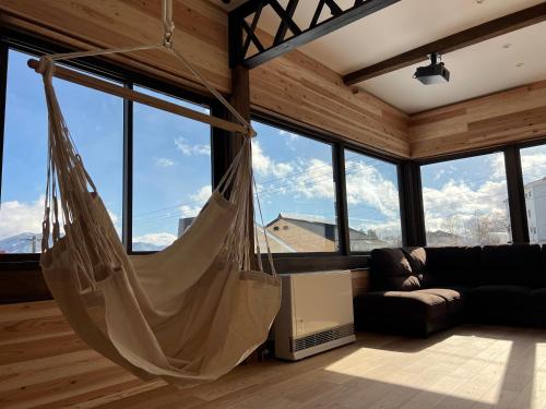 a hammock hanging in a room with windows at KONAYUKI Apartment in Myoko