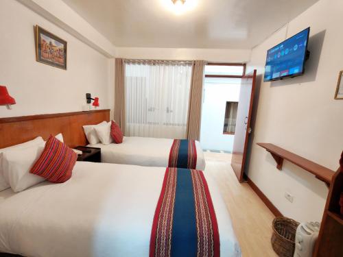 a hotel room with two beds and a flat screen tv at Saphi Inn Cusco - Excelente ubicación in Cusco