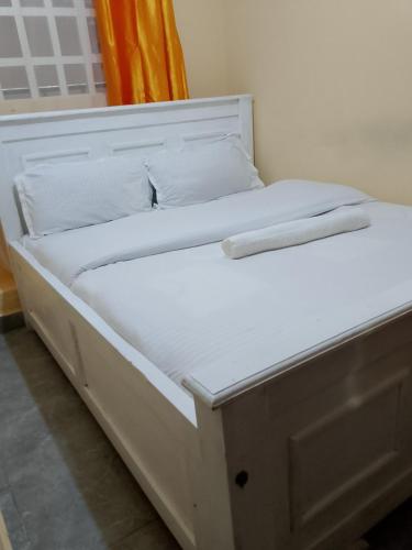 a bed with white sheets and pillows on it at Mwembe Airbnbs in Kisii
