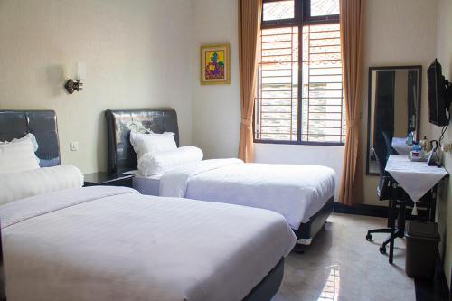 a hotel room with three beds and a window at Salak Cozzy Stay Managed by Salak Hospitality in Kamparganya