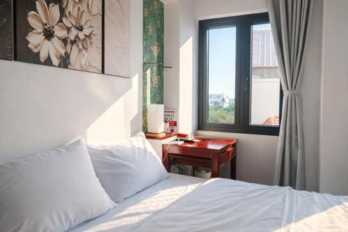 a bedroom with a bed and a desk next to a window at ICHI Home Kim Long in Hue