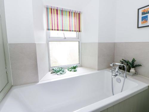a white bath tub in a bathroom with a window at Rose Cottage in Cardigan