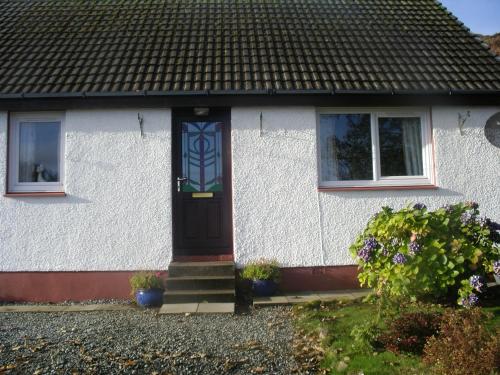 a white house with a blue door and windows at Sonas, Dunans in Flodigarry