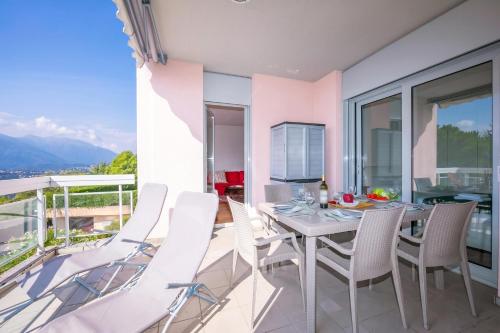 a dining room with a table and chairs on a balcony at La Maison du Bonheur with Shared Pool & Sauna - Happy Rentals in Aldesago