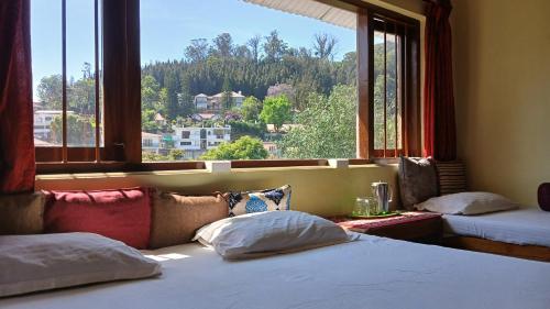 a bedroom with two beds and a large window at Satya Anand Pure Veg and Non Alcoholic Cottage in Coonoor