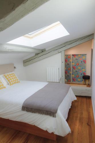 - une chambre avec un grand lit blanc et une lucarne dans l'établissement La Loge du 12, à Bordeaux