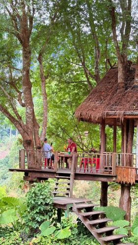 a wooden tree house with two people on it at Namdong Waterfall & Eco Resort in Luang Prabang