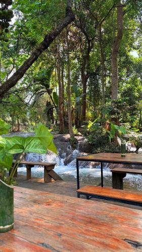 two benches sitting on a deck near a river at Namdong Waterfall & Eco Resort in Luang Prabang