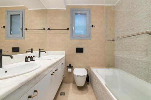 a bathroom with two sinks and a tub and a toilet at Villa Aristoteles in Lindos