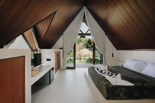 a bedroom with a large bed with a wooden ceiling at Limbo Lux Bungalows in Kuta Lombok