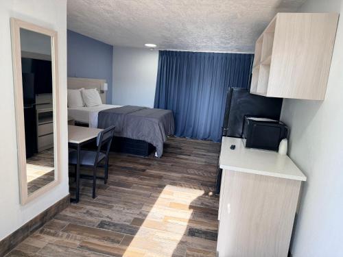 a hotel room with a bed and a desk and a table at Bravo Inn Greensboro in Greensboro