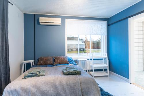ein Schlafzimmer mit einem Bett, blauen Wänden und einem Fenster in der Unterkunft Matmalmen E&A in Pargas
