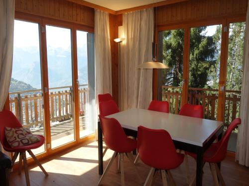 a dining room with a table and red chairs at Cozy apartment for groups in Veysonnaz