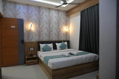 a bedroom with a large bed with blue pillows at Hotel Heritage Prime Junagadh in Junagadh