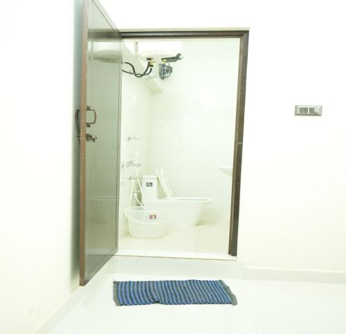 a bathroom with a shower and a toilet and a rug at La Coral Residency in Pondicherry
