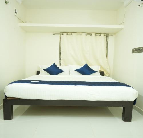 a bed with blue pillows in a white room at La Coral Residency in Pondicherry