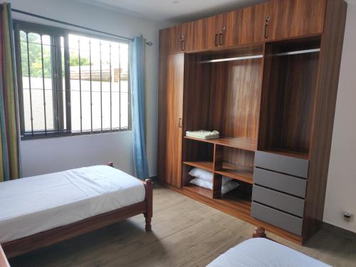 a bedroom with a bed and a cabinet and a window at mahogany villa in Grand-Baie