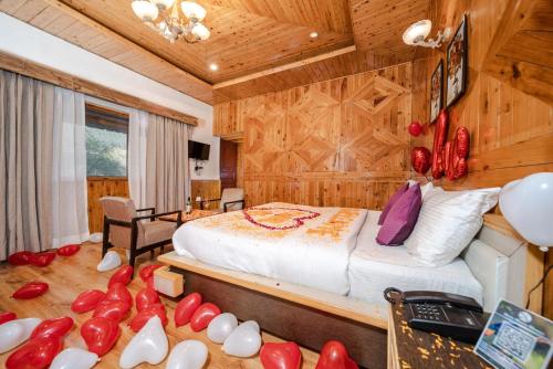 a bedroom with a bed with red balloons on the floor at Hotel Monal in Manāli