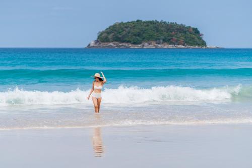 a woman standing on the beach with a frisbee at Kata Beach Pool View Condo - 400m from the Beach in Kata Beach