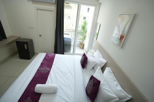 a bedroom with a large bed with purple and white pillows at Hotel Flamount Arka Studios in Hyderabad