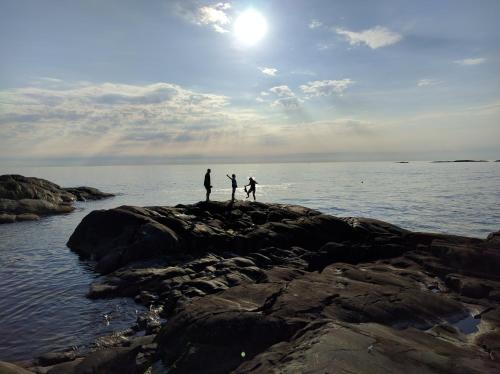 three people standing on the rocks near the water at Lekanders Bär & Boende in Tyfta