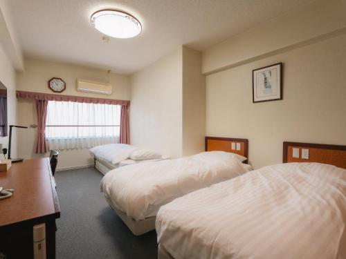 a hotel room with two beds and a desk at Hotel Union in Kagoshima