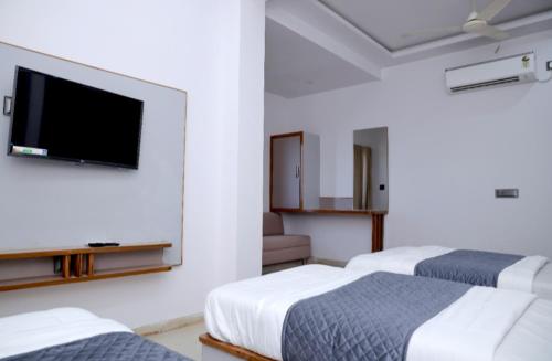 ein Hotelzimmer mit zwei Betten und einem Flachbildfernseher in der Unterkunft Hotel Excellency in Dīsa