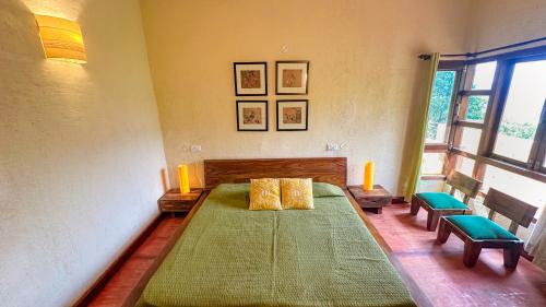 a bedroom with a large bed with two green chairs at Pillow on the Cloud in Rāmgarh