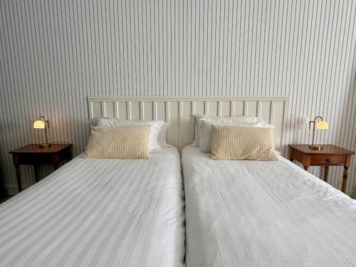two beds with white sheets and pillows in a bedroom at Hôtel de la Marine Saint Herblain in Saint-Herblain