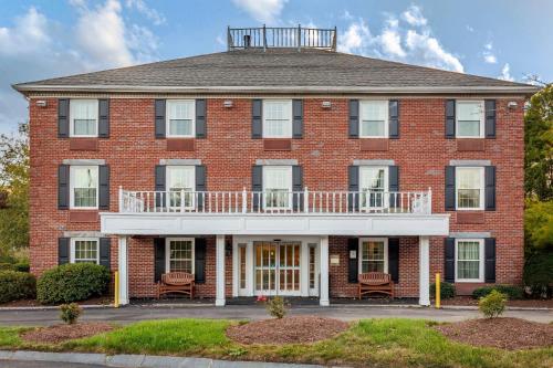 a large red brick building with a white balcony at Comfort Inn Foxboro - Mansfield in Foxborough